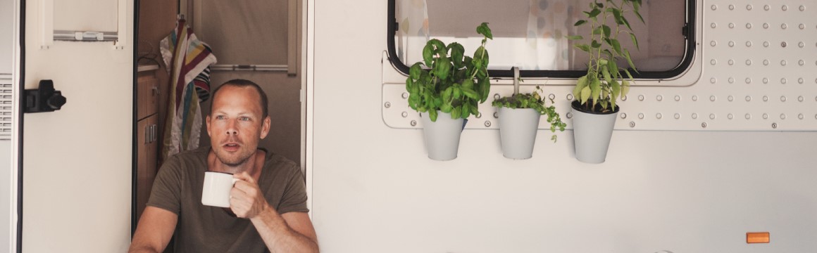 man zittend in deuropening caravan