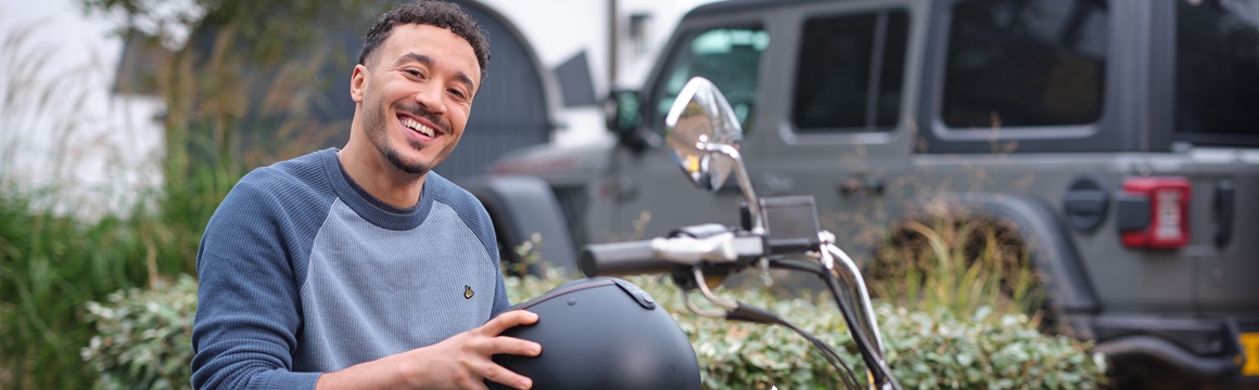 man op motor met helm in handen