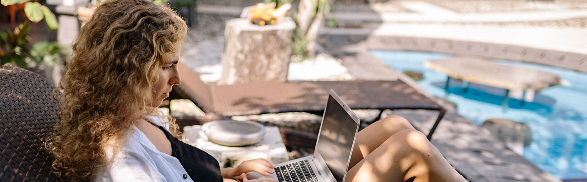 vrouw op laptop aan het zwembad