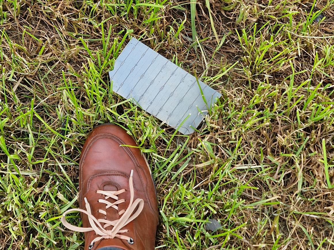 Zonnepaneeldeeltje in het gras na een brand