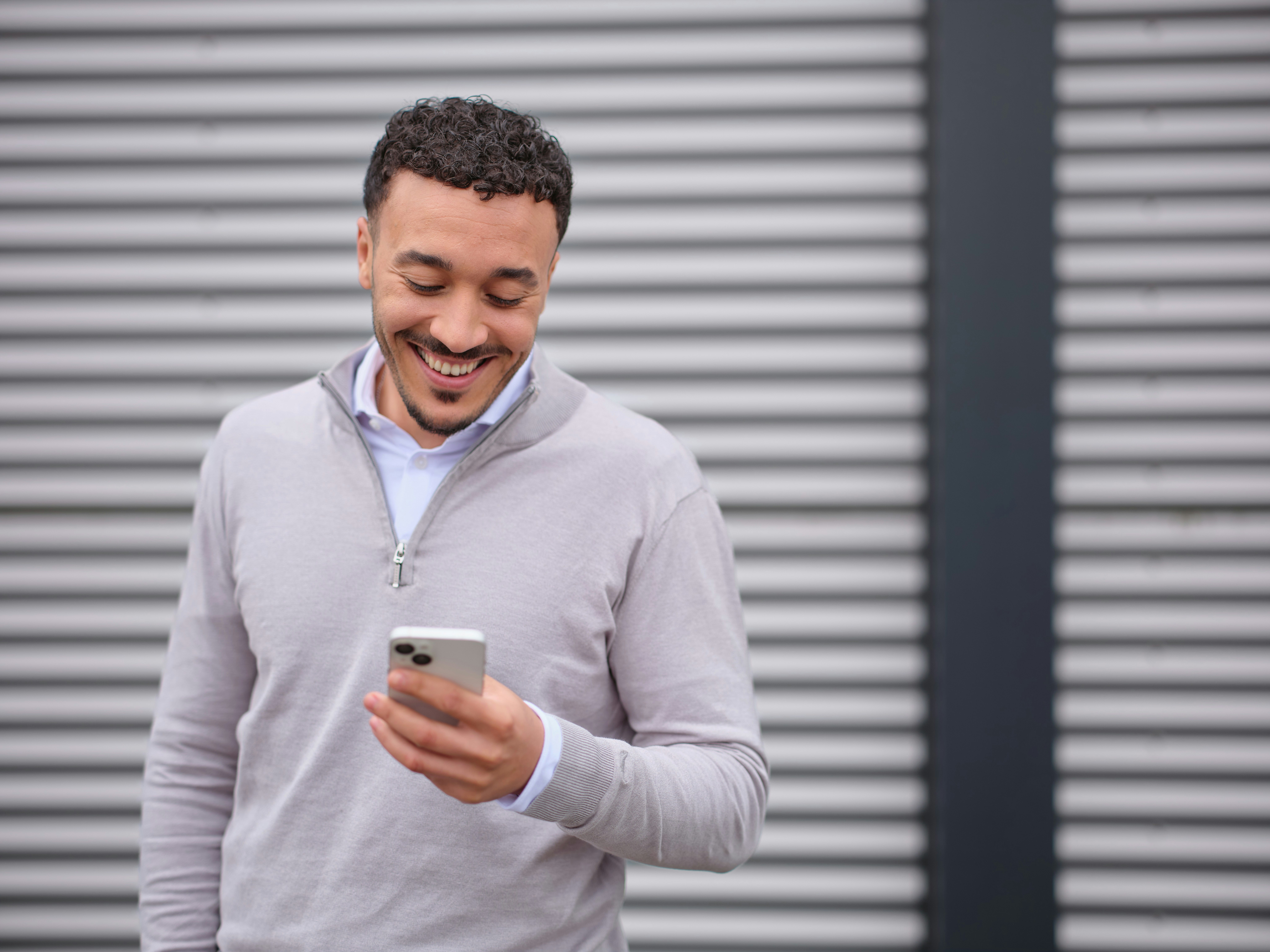 Man voor grijs gebouw op telefoon