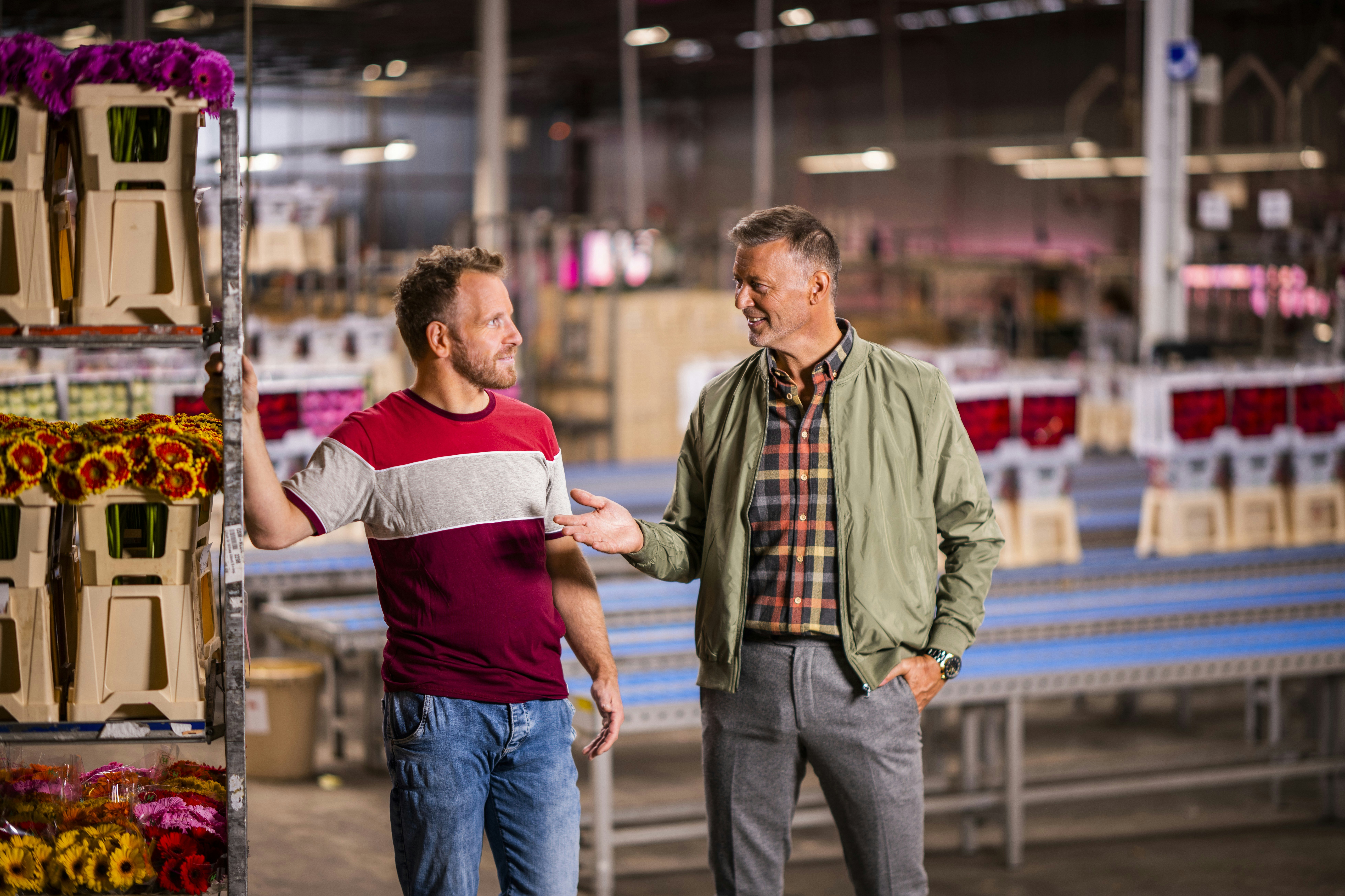 Ondernemer en adviseur staan naast stelling met bloemen