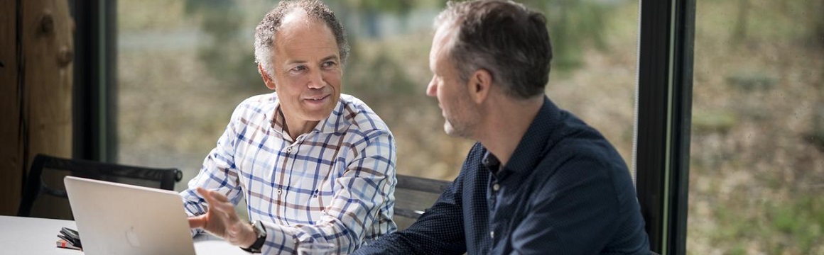 2 mannen in gesprek achter laptop
