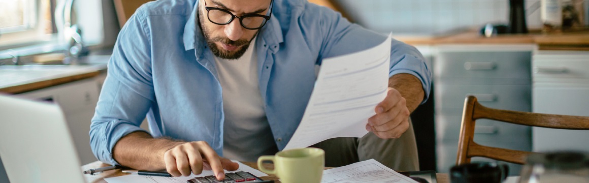 man tussen de papieren met rekenmachine