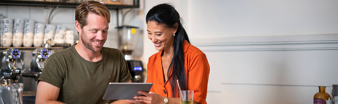 man en vrouw kijken naar tablet in horecazaak